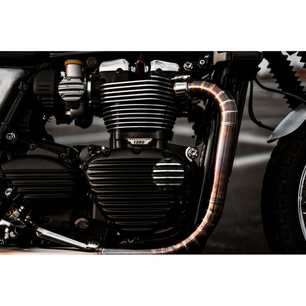Close-up of a motorcycle engine with a shiny copper exhaust pipe.